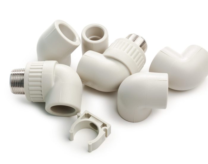 Different types of plastic plumbing pieces are placed on a plain white background for repair use.